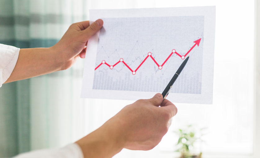 Homem segurando um gráfico de crescimento da produtividade têxtil em uma confecção.