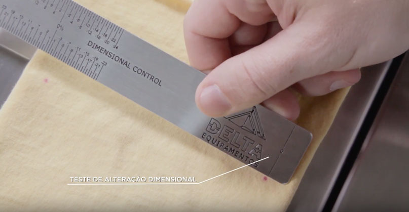 Técnico fazendo medição do teste dimensional em uma amostra de matéria-prima na indústria têxtil.