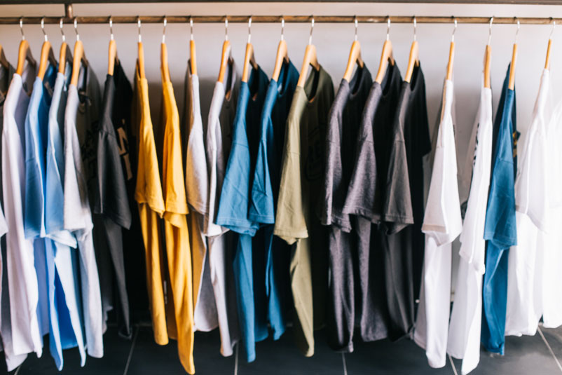 Camisetas recém produzidas com matéria-prima de alta qualidade penduradas em uma arará, são o resultado de uma modernização constante na indústria têxtil. 