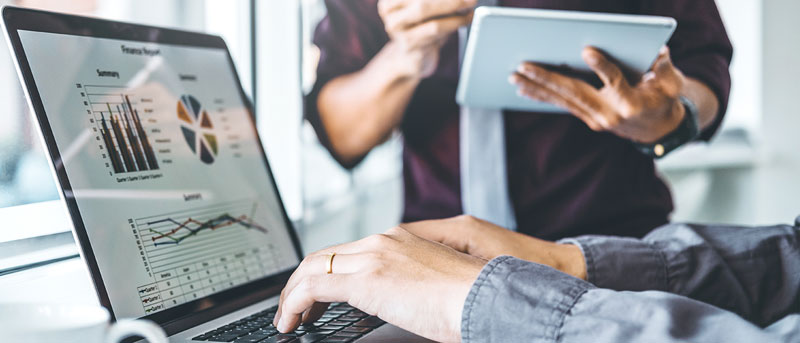 Duas pessoas em uma reunião de uma empresa fast fashion analisando dados produtivos.